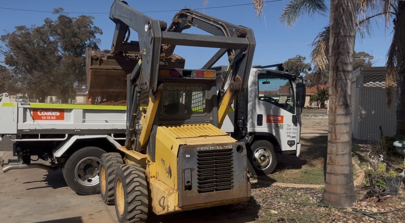 Skid steer working in tight side access